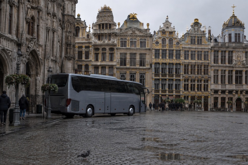 A tour coach parked on a cobbled square in a European old town