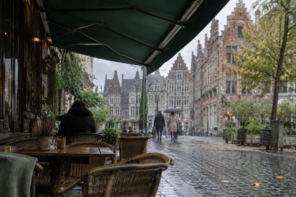 A narrow European street with old buildings and a cafe awning