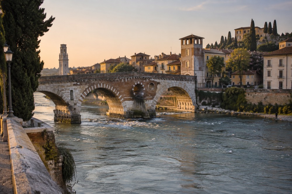 A stone bridge over a river with historic European buildings on both banks