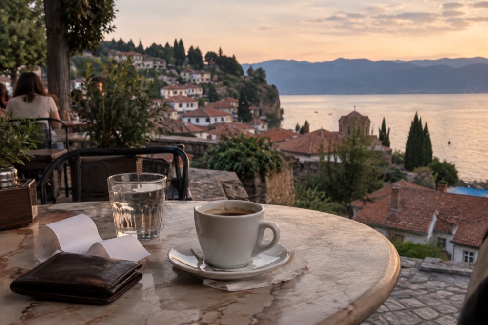 A wallet and receipt on a cafe table beside a coffee cup