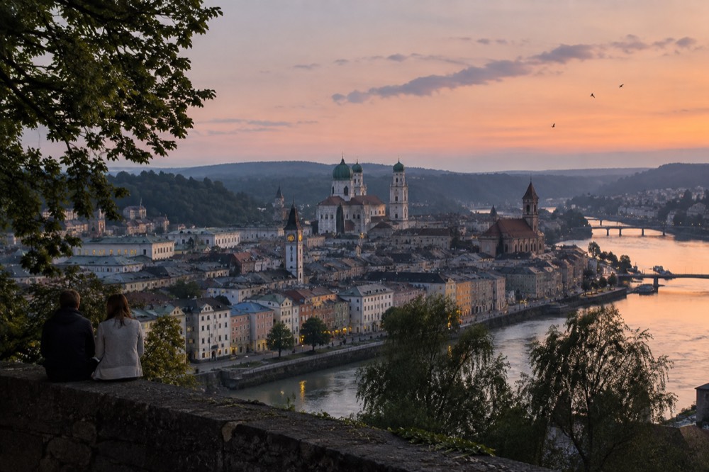 Baroque church spires and pastel facades of an old European town square at dusk