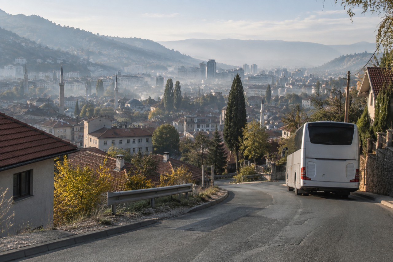 A coach parked on a mountain road above a European valley with stone villages in the distance