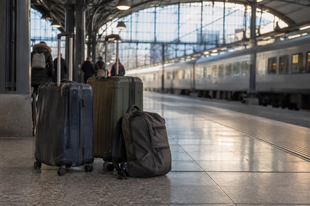 Tourist luggage on a European train platform beside a station building