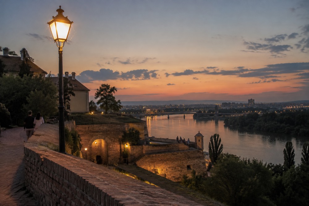 Fortress walls above a river confluence at dusk in a Balkan capital city
