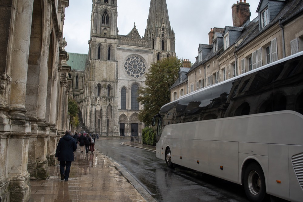 A touring coach parked outside a grand cathedral on a city street