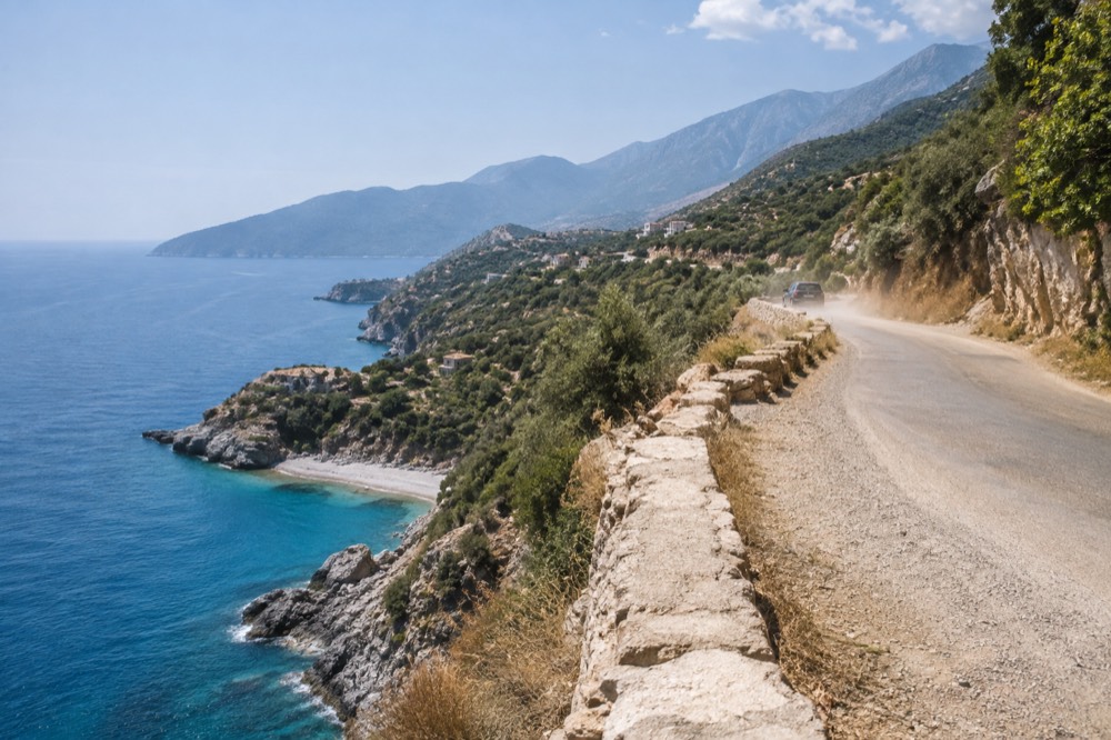 Coastal road curving along a cliff above a turquoise sea