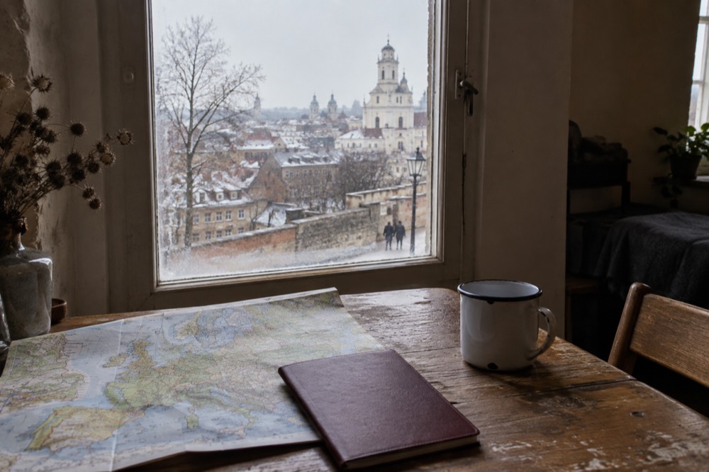 A passport resting on a wooden table beside a folded map of Europe