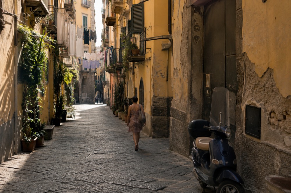 A narrow European old town street with modest guesthouse facades and hanging laundry