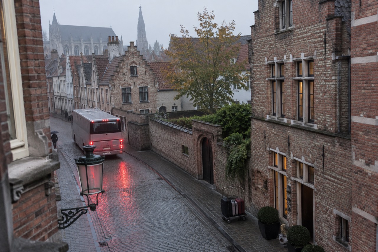 A coach parked on a cobblestone street beside old European buildings in morning light