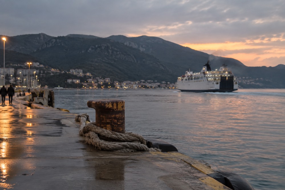 A ferry terminal on the Adriatic coast with a boat departing at dusk