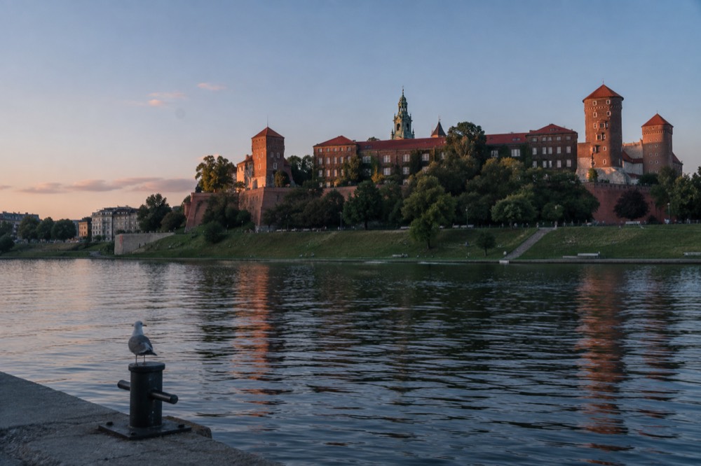 A riverfront city skyline with a castle on a hill at dusk