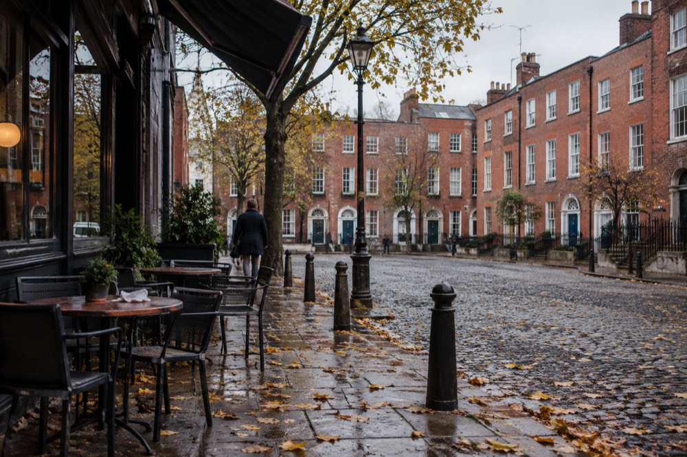 A European old town square in autumn with leaves on the cobbles and cafe tables outside