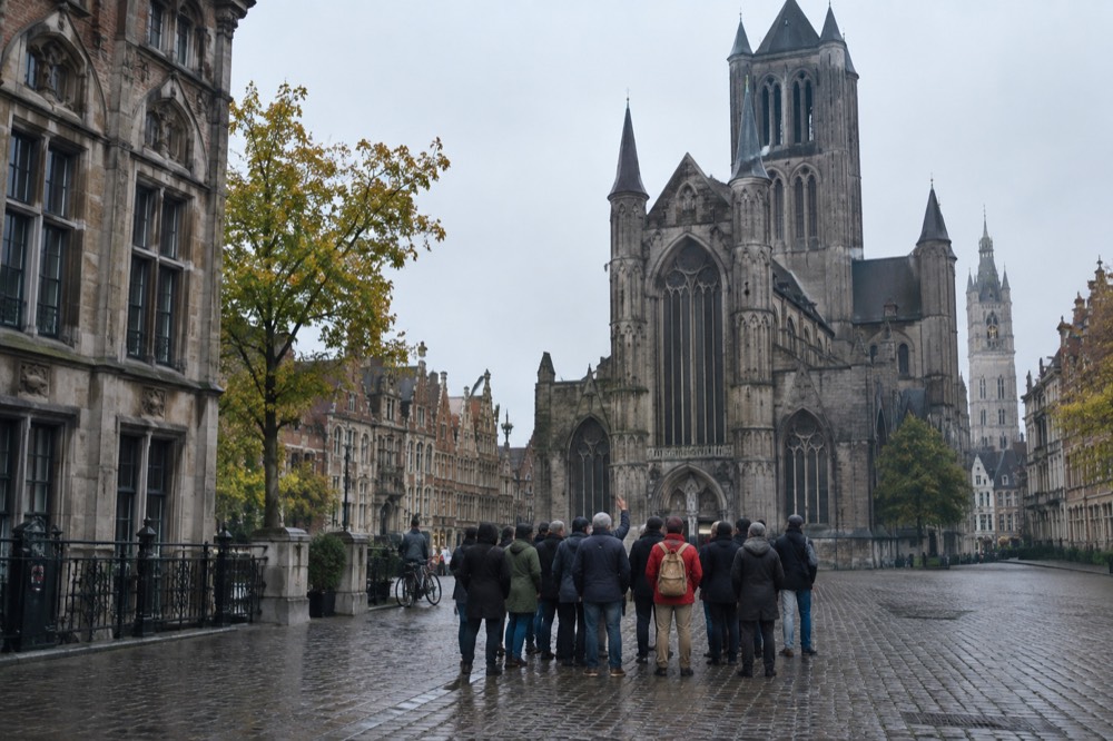 A tour manager with a small group listening to a commentary outside a European cathedral