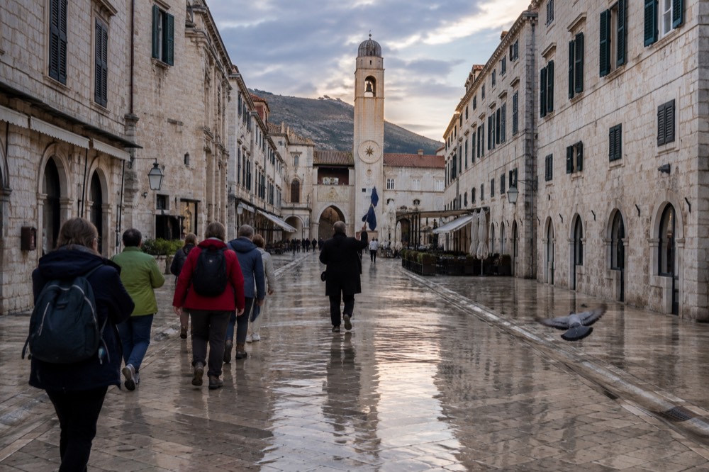 Small group of travellers walking with a tour leader through a European old town square