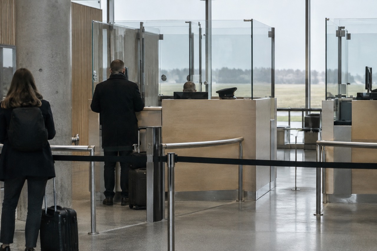 Passport control booths at a European airport border crossing with clear signage