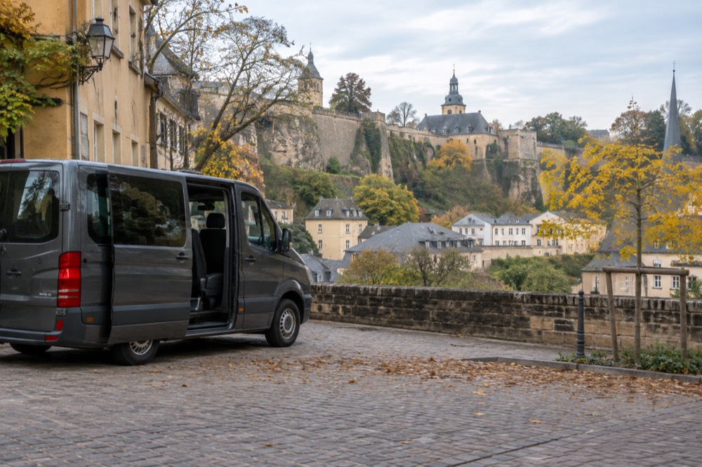 A small minibus parked on a cobbled square in a historic European town