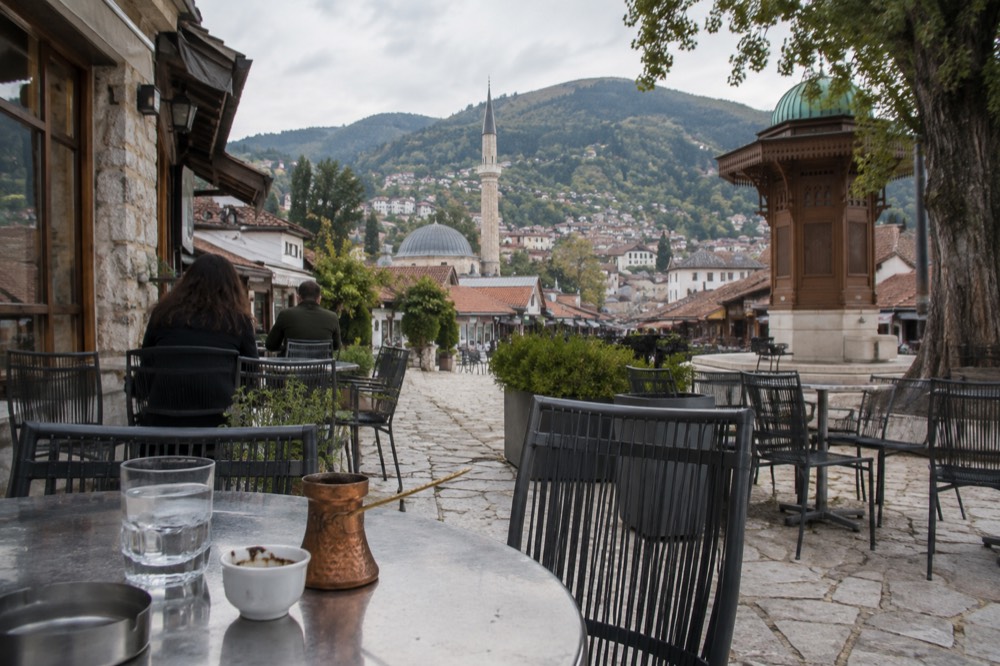 A terrace cafe in a Balkan old town with mountains rising behind the rooftops