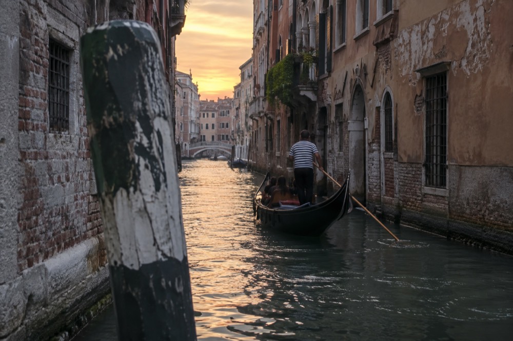 A gondola on a narrow canal between old stone buildings