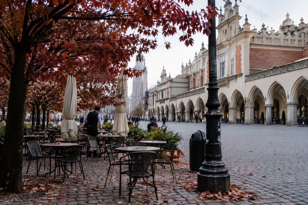 A European city square with outdoor café tables and autumn trees