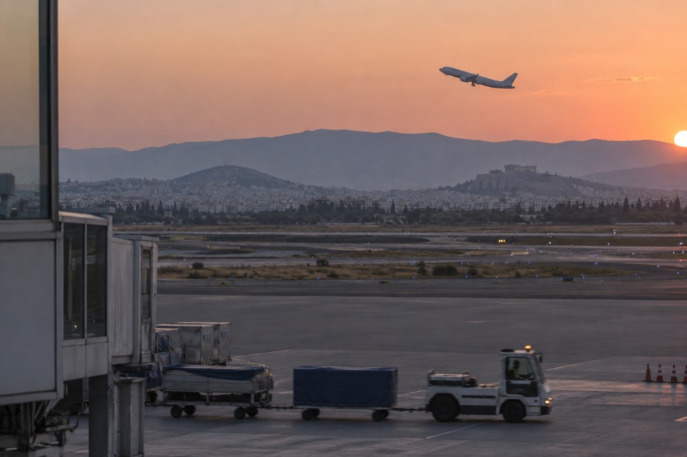 An aircraft climbing above clouds after takeoff from an airport at dusk