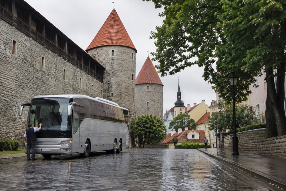 A coach parked on a cobblestone square beside historic European buildings