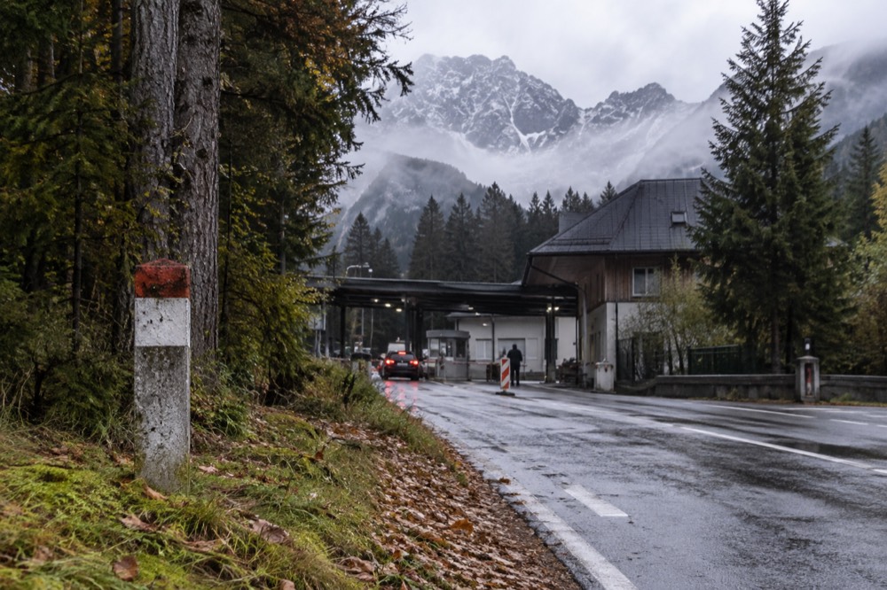 A border crossing sign on a quiet road between two European countries