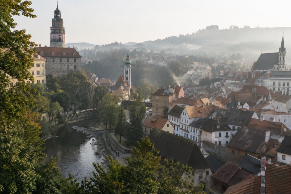 A historic European old town square with pastel coloured buildings and a stone cathedral tower