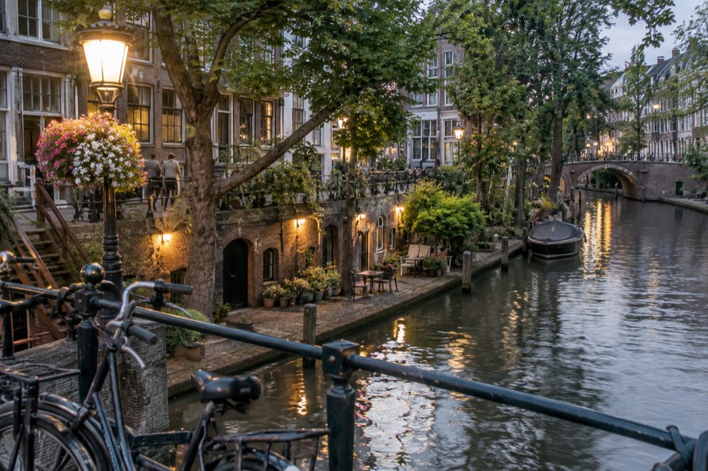 A canal in a Dutch city with narrow brick houses and bicycles on a bridge