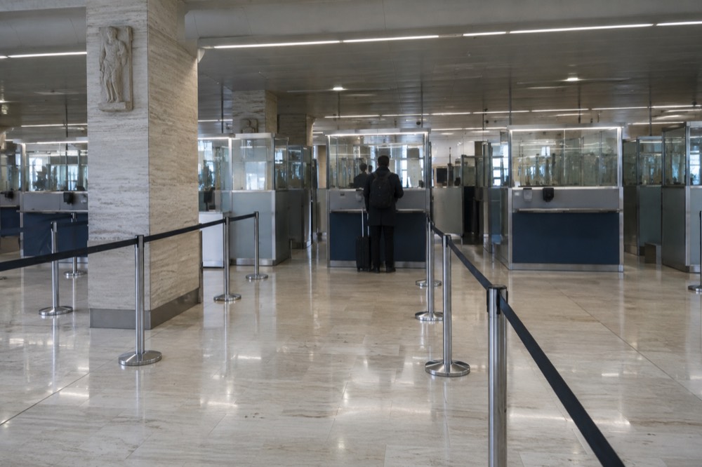 Passport control booths at an airport border with signage overhead