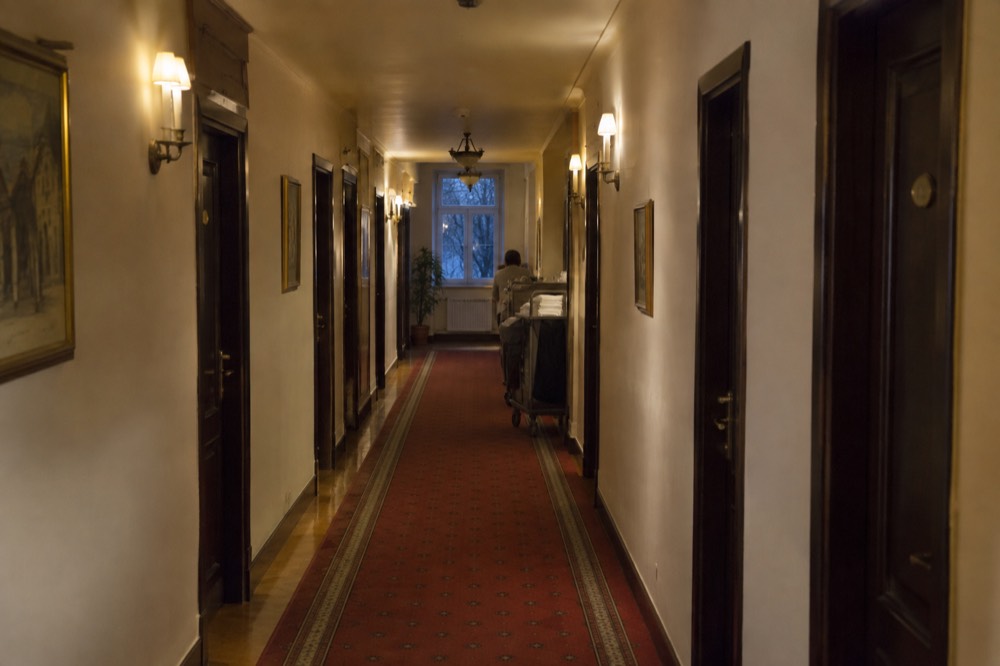 A quiet hotel corridor with numbered doors and warm lamplight in an old European building