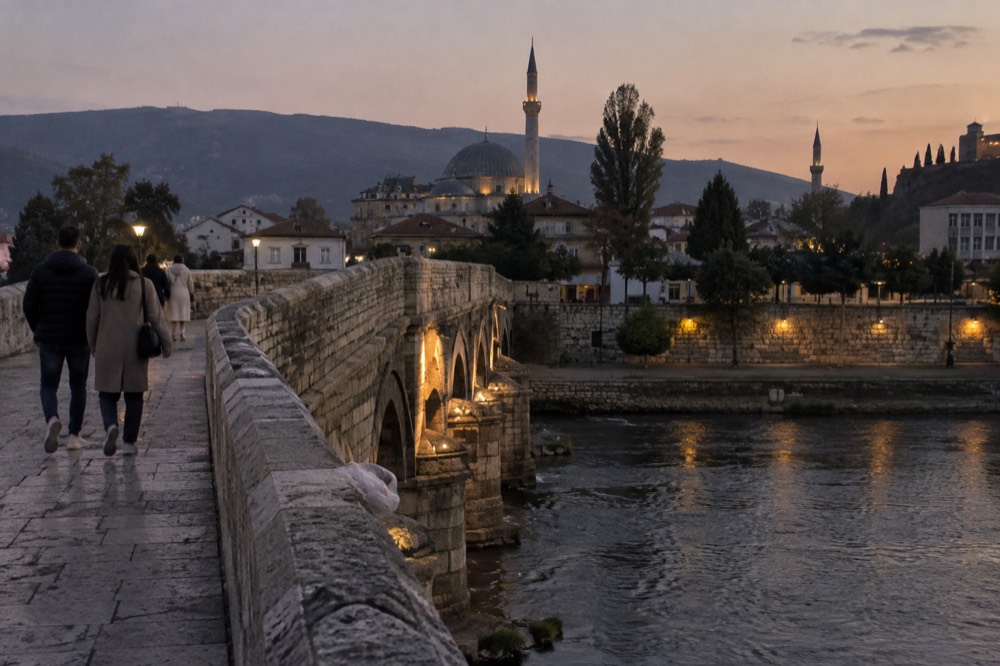 A stone bridge over a river in a Balkan old town at dusk